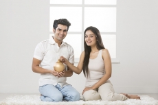 newly wed couple at new home with piggy bank