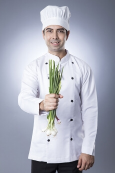 chef posing with spring onions 
