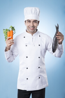 chef posing with fish and carrots