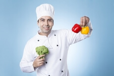 chef posing with capsicums and broccoli