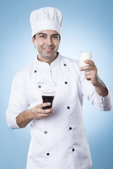 chef posing with glass of milk and soft drink