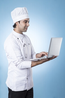 chef smiling and posing with laptop