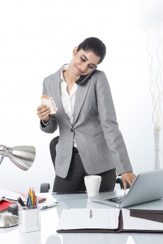 modern woman eating sandwich while working 
