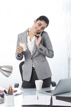 modern woman eating sandwich while working 