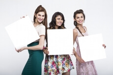 three young women posing with message board