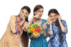 three women standing together holding vegetable in hand