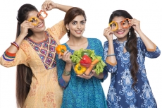 three women standing together holding vegetable in hand