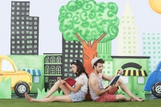 couple sitting back to back in garden reading book