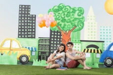 couple sitting back to back in garden holding balloons