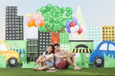 couple sitting back to back in garden holding balloons