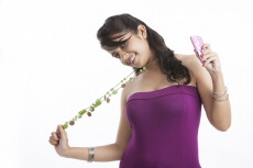teen girl holding long bead necklace with cell phone