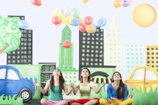 Three girls sitting on grass and floating balloons