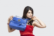 young female carrying a blue handbag while posing